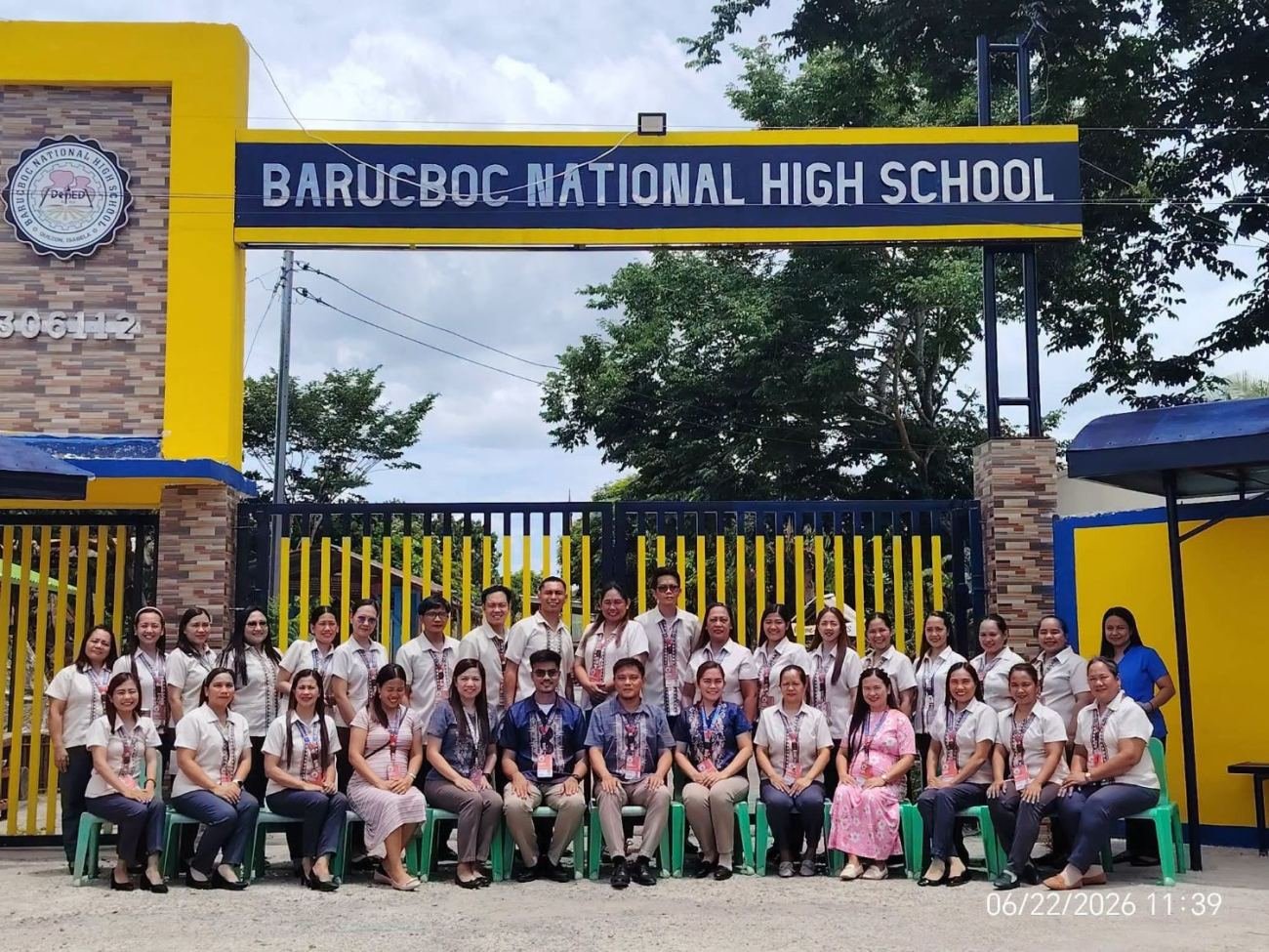 Teachers and staff of Barucboc National High School posing together in front of the school gate